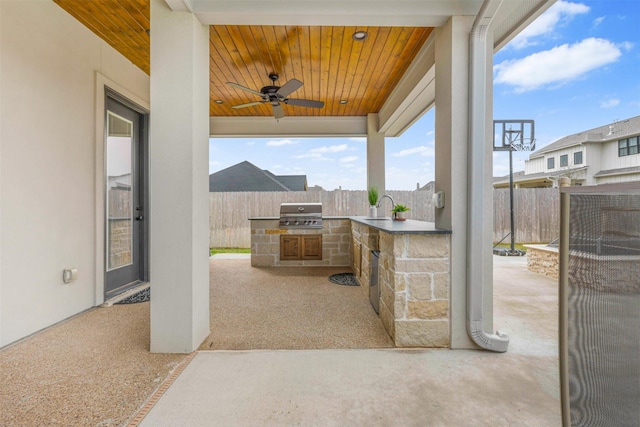 view of patio / terrace with an outdoor kitchen, area for grilling, ceiling fan, fence, and a sink