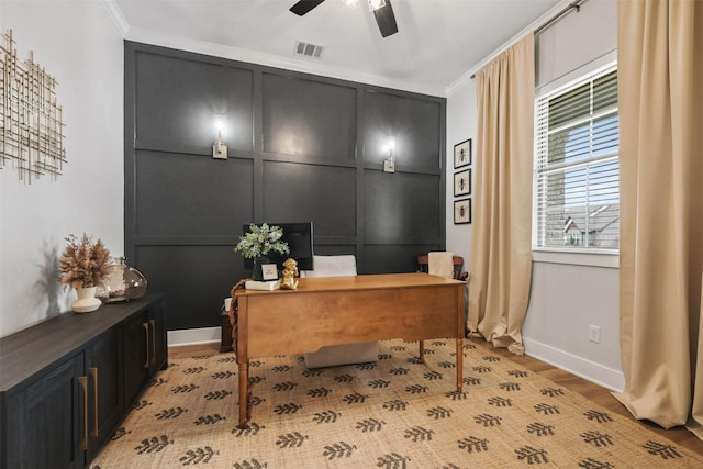 office area featuring visible vents, a decorative wall, ceiling fan, light wood-type flooring, and baseboards