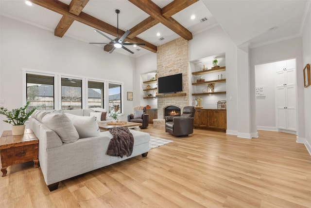 living area featuring a stone fireplace, coffered ceiling, baseboards, light wood-style floors, and beamed ceiling