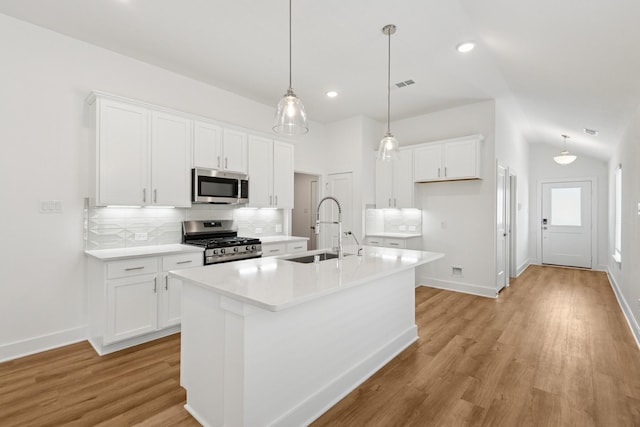 21659 Wave Hollow Dr, Cypress, TX 77433 - kitchen with appliances with stainless steel finishes, decorative backsplash, white cabinets, light wood-style floors, and vaulted ceiling