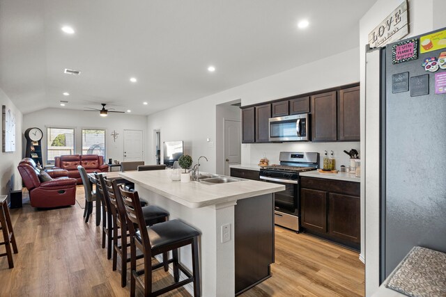 1730 Windstone Ridge Dr, Houston, TX 77014 - kitchen with appliances with stainless steel finishes, a kitchen breakfast bar, dark brown cabinets, light wood finished floors, and recessed lighting