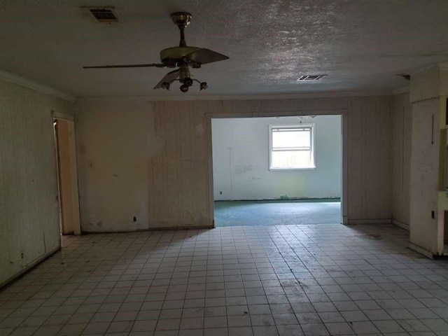 empty room with a textured ceiling, visible vents, a ceiling fan, and ornamental molding