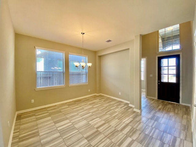 foyer entrance with visible vents, baseboards, and an inviting chandelier