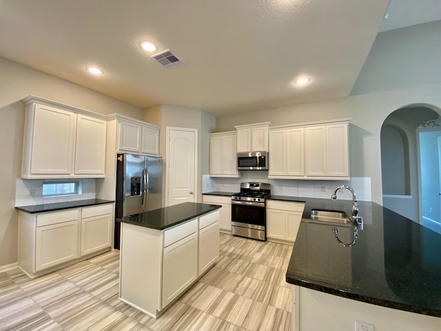 kitchen featuring a peninsula, white cabinets, stainless steel appliances, and a sink