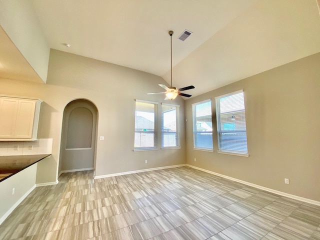 interior space with lofted ceiling, visible vents, arched walkways, and baseboards