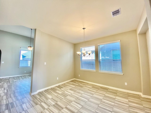 spare room featuring ceiling fan with notable chandelier, visible vents, and baseboards