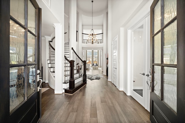 entryway featuring baseboards, stairway, dark wood-type flooring, a high ceiling, and a notable chandelier