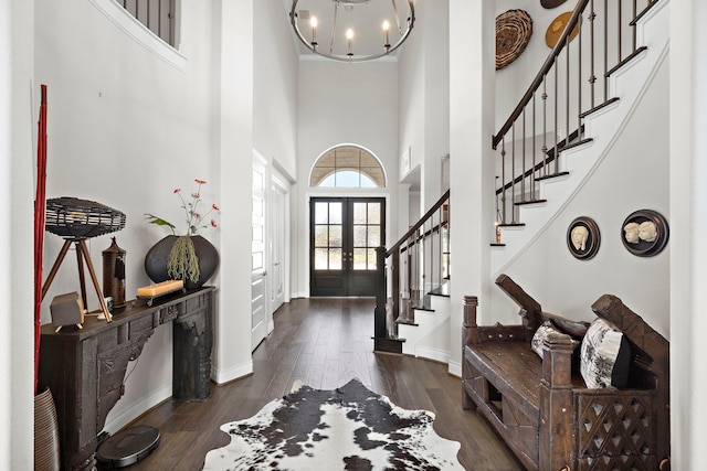 foyer featuring baseboards, dark wood-style flooring, stairs, french doors, and a notable chandelier