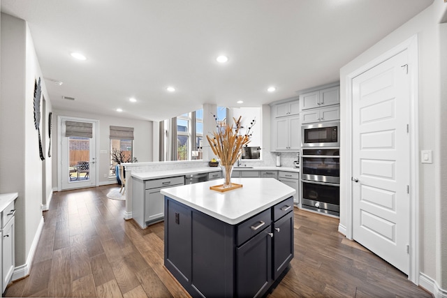 kitchen with light countertops, appliances with stainless steel finishes, gray cabinets, and a kitchen island