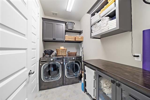 laundry area featuring cabinet space, independent washer and dryer, and visible vents