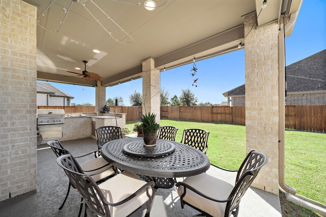 view of patio / terrace with ceiling fan, a grill, an outdoor kitchen, and a fenced backyard