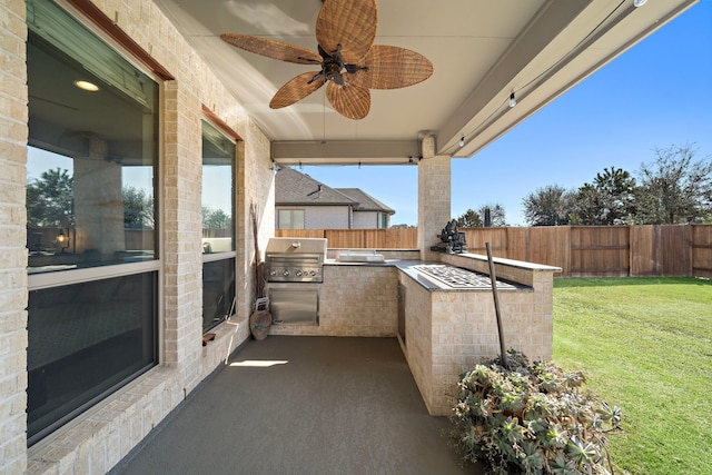 view of patio / terrace with fence, a ceiling fan, grilling area, and exterior kitchen