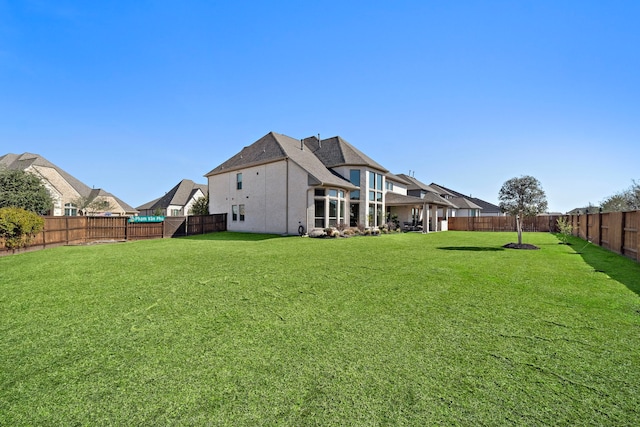 rear view of house with a fenced backyard and a yard