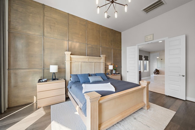 bedroom featuring an inviting chandelier, visible vents, and wood finished floors