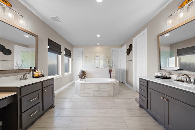 full bathroom with two vanities, visible vents, a sink, and a bath