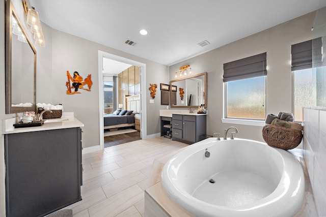 full bath featuring a freestanding tub, connected bathroom, visible vents, and two vanities