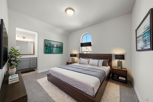 bedroom featuring ensuite bath, baseboards, and light colored carpet