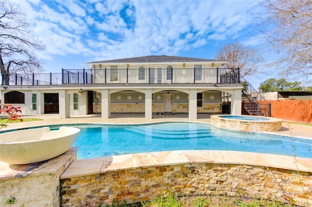 view of pool featuring a pool with connected hot tub, a patio area, fence, and stairs