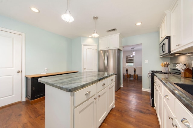 kitchen with white cabinets, dark wood finished floors, a kitchen island, appliances with stainless steel finishes, and pendant lighting