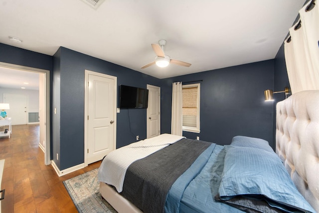 bedroom featuring a ceiling fan, baseboards, and dark wood-style flooring