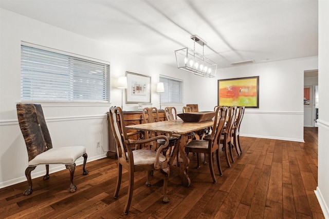 dining area featuring a notable chandelier, visible vents, baseboards, and dark wood-style flooring