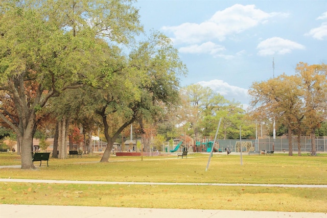 view of community featuring playground community, a yard, and fence