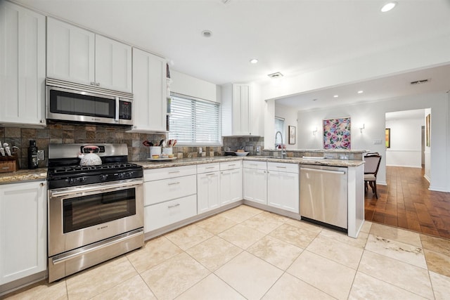 kitchen with light stone counters, appliances with stainless steel finishes, and white cabinetry