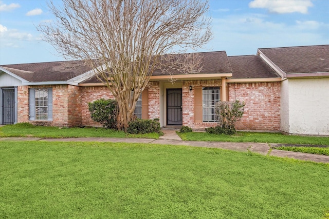 ranch-style home featuring brick siding, a front lawn, and roof with shingles