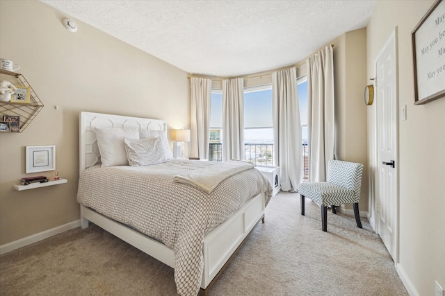bedroom with light colored carpet, a textured ceiling, and baseboards
