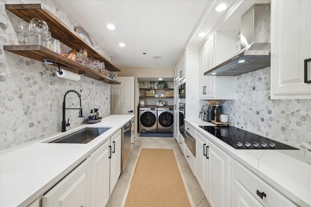 kitchen with washing machine and dryer, open shelves, a sink, white cabinets, and wall chimney exhaust hood
