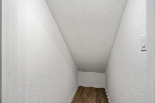 interior space with baseboards, wood finished floors, and a textured wall