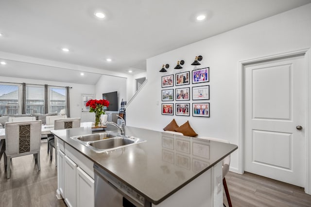 kitchen featuring a center island with sink, dishwasher, open floor plan, white cabinetry, and a sink