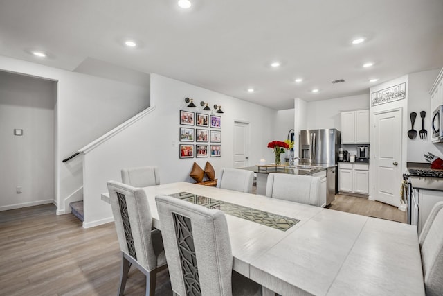 dining room featuring light wood-type flooring, stairway, and recessed lighting