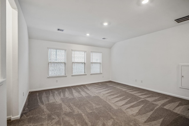 spare room featuring baseboards, visible vents, vaulted ceiling, dark colored carpet, and recessed lighting