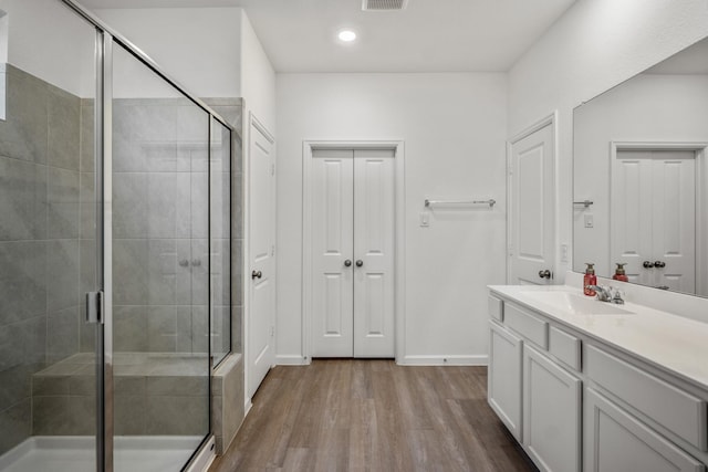 bathroom featuring visible vents, a shower stall, vanity, and wood finished floors