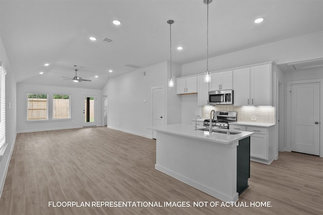 kitchen with light countertops, appliances with stainless steel finishes, open floor plan, white cabinetry, and a sink