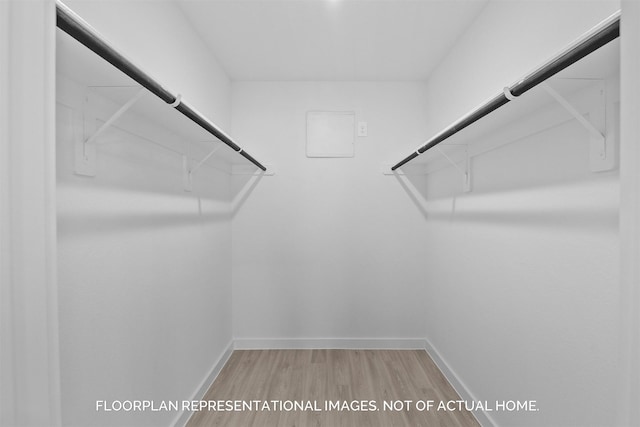 spacious closet with attic access and light wood-type flooring