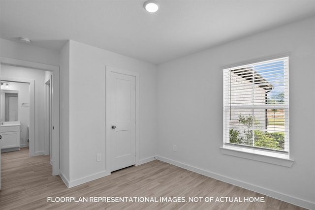 unfurnished bedroom featuring light wood-type flooring, multiple windows, and baseboards