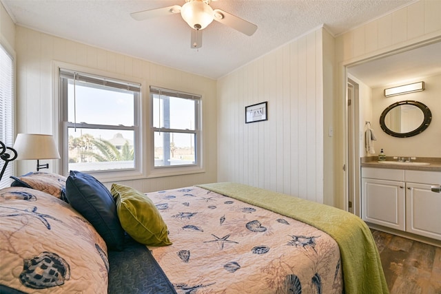 bedroom featuring a textured ceiling, a sink, a ceiling fan, dark wood-style floors, and crown molding