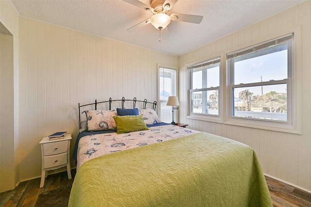 bedroom featuring a ceiling fan, dark wood finished floors, and a textured ceiling