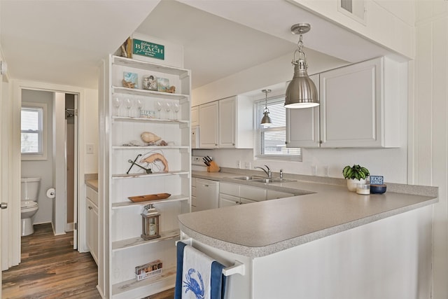 kitchen featuring pendant lighting, white cabinets, a sink, dishwasher, and a peninsula