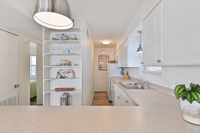 kitchen featuring open shelves, light countertops, stove, white cabinets, and a sink