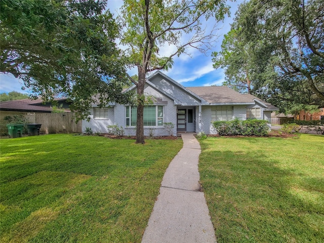 ranch-style home with brick siding, fence, and a front lawn