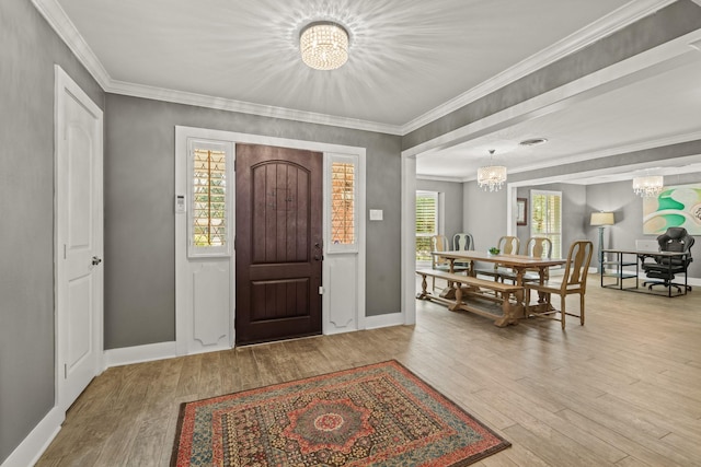 foyer entrance featuring wood finished floors, a healthy amount of sunlight, and an inviting chandelier