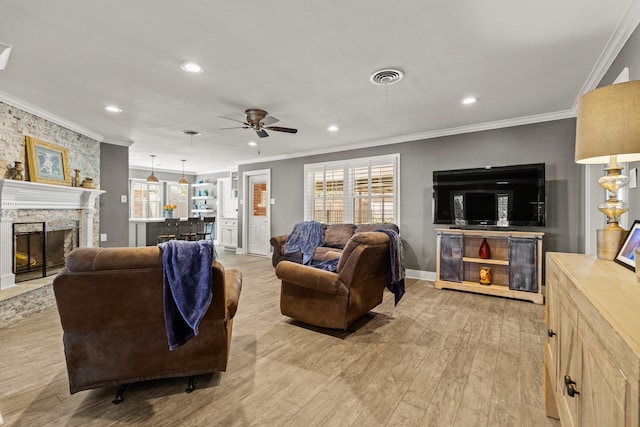 living room featuring a healthy amount of sunlight, light wood-type flooring, a fireplace, and crown molding