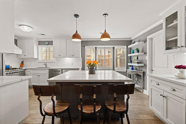 kitchen featuring light stone countertops, glass insert cabinets, white cabinets, and pendant lighting