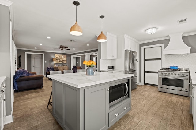 kitchen with stainless steel appliances, premium range hood, a kitchen breakfast bar, open floor plan, and a center island