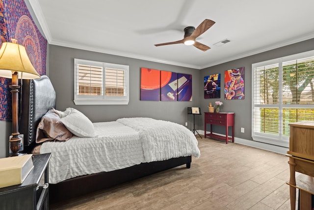 bedroom featuring ceiling fan, visible vents, baseboards, light wood-style floors, and crown molding