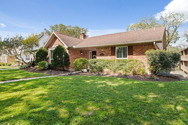 ranch-style home featuring a front yard, brick siding, a chimney, and roof with shingles