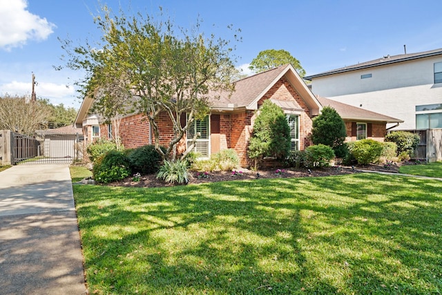 ranch-style house featuring a shingled roof, a gate, brick siding, and a front lawn